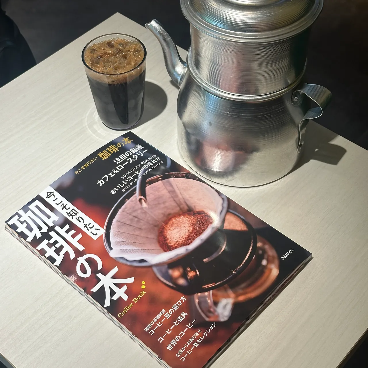 バインミーシンチャオのコーヒーグラスとフィンコーヒー器具と並んだ『Coffee Book』の表紙。写真：QUY DANG