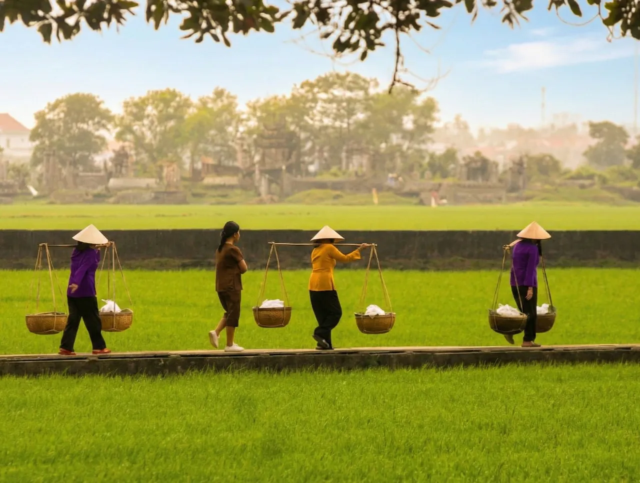 Women of Van Cu village recreating the scene of carrying fresh vermicelli across the fields. Photo: Vo Thanh - VN Express